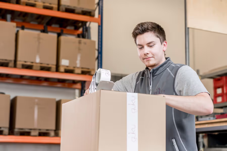 Güku Mitarbeiterin verschließt Umverpackung
